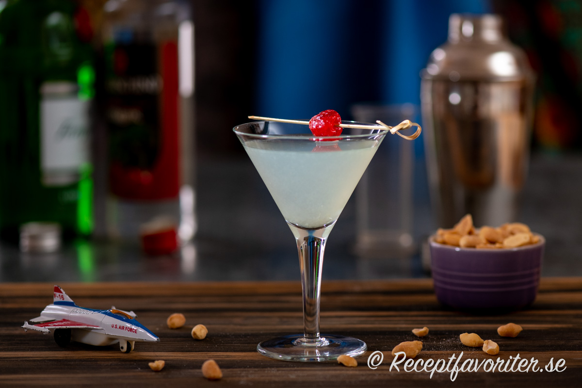 Aviation cocktail serverad i martiniglas med jordnötter vid sidan.