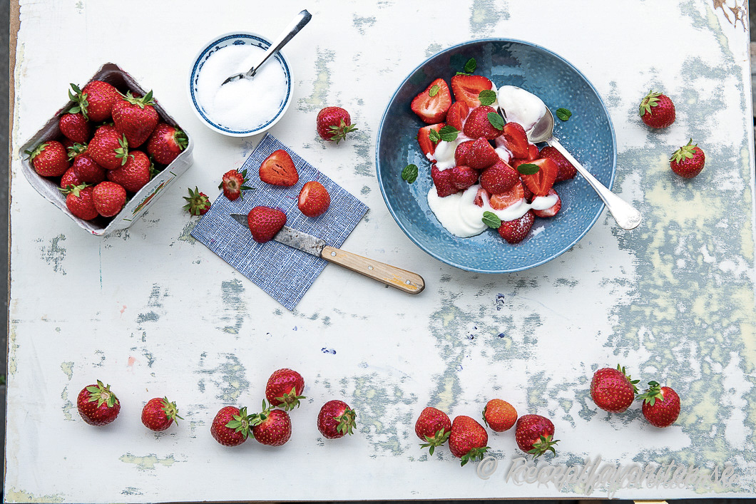 Svenska söta jordgubbar på bricka med grädde och socker