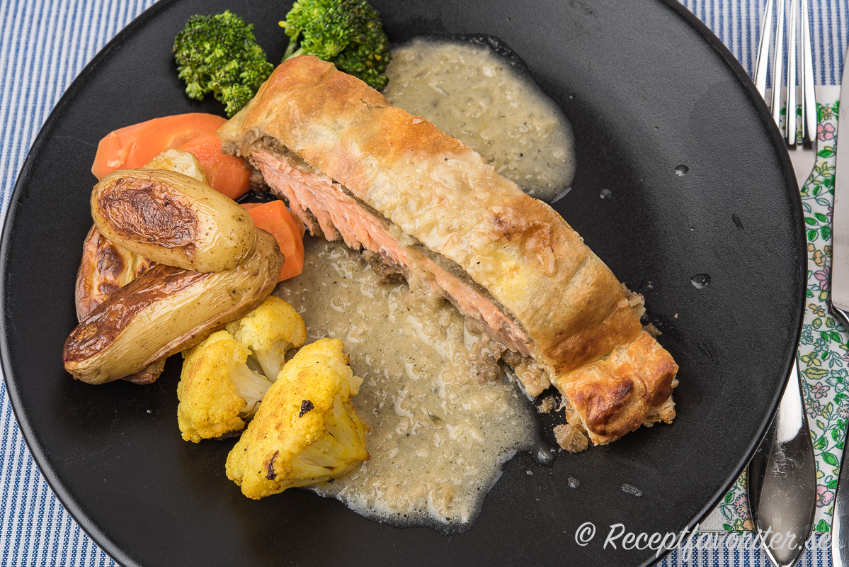 Lax Wellington serverad med en smörsås, rostad potatis och blomkål samt kokt morot och broccoli.  