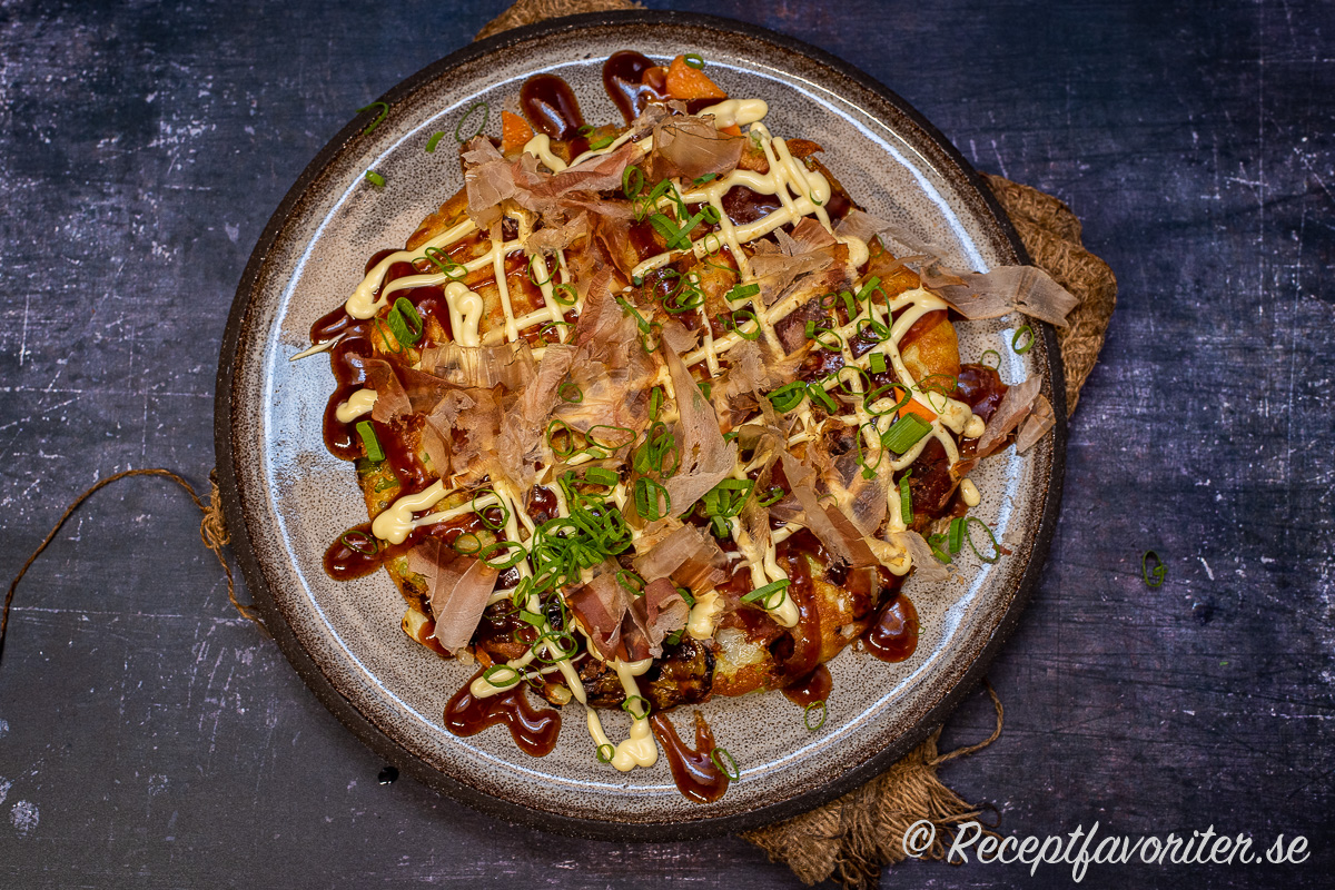 Okonomiyaki är en slags grönsakspannkaka som serveras med japansk majonnäs, Okonomiyaki-sås, katsuobushi torkad fisk samt strimlad salladslök. 