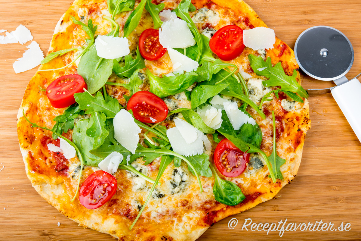 Hembakt gorgonzola- eller ädelostpizza med ruccola, tomat och hyvlad parmesan. 