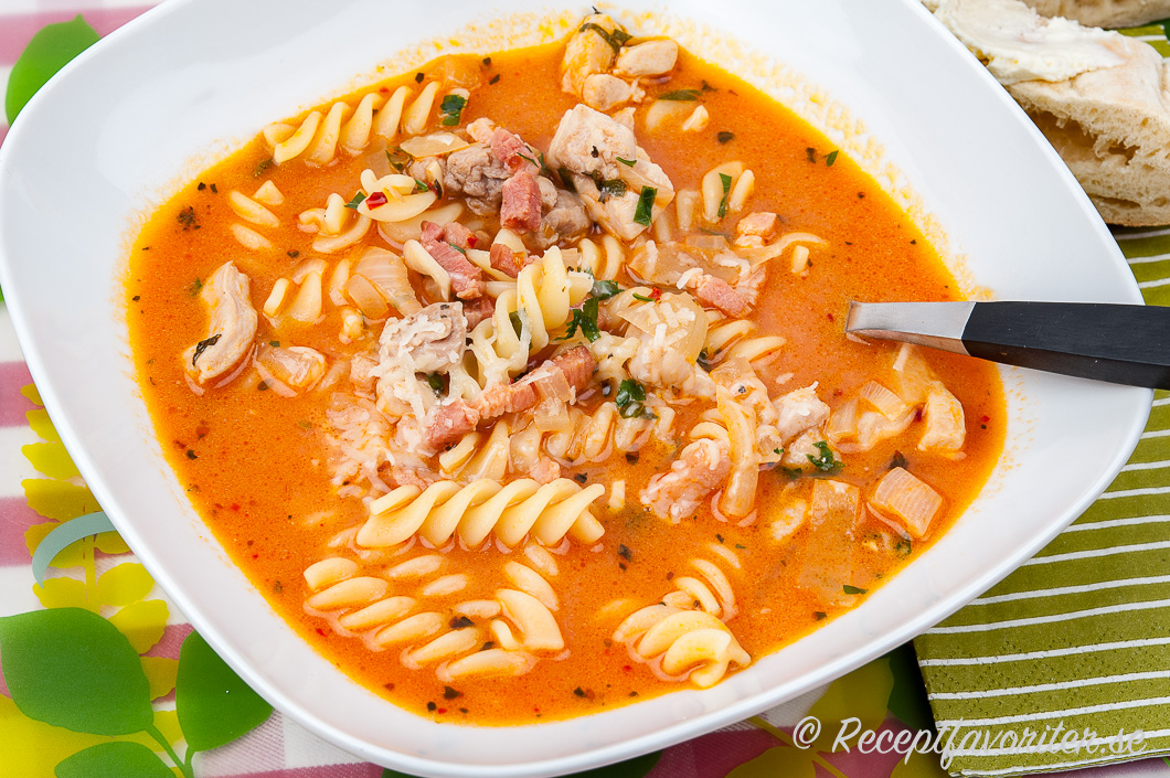 Soppa med pastaskruvar och bacon i tallrik