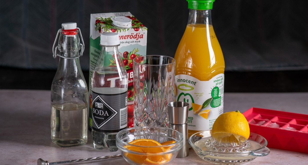 Till drinken behöver du sockerlag, sodavatten, tranbärsjuice, färsk apelsin, highballglas, rörsked, cl mått, apelsinjuice, citron och is. 