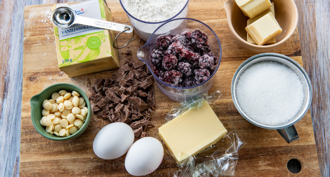 Ingredienser till kakan: vita chokladknappar, vaniljsocker, ägg, mjölkchoklad, smör, vetemjöl, färska eller frysta björnbär, socker och vit choklad. 