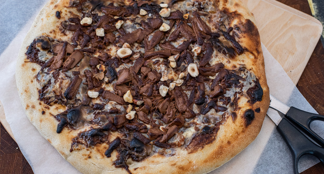 Först gräddas pizzan med enbart crème fraiche och nutella. Strö sedan över riven choklad och grädda några sekunder tills den smält och fått färg. Strö över rostade nötter och lägg på banan. 