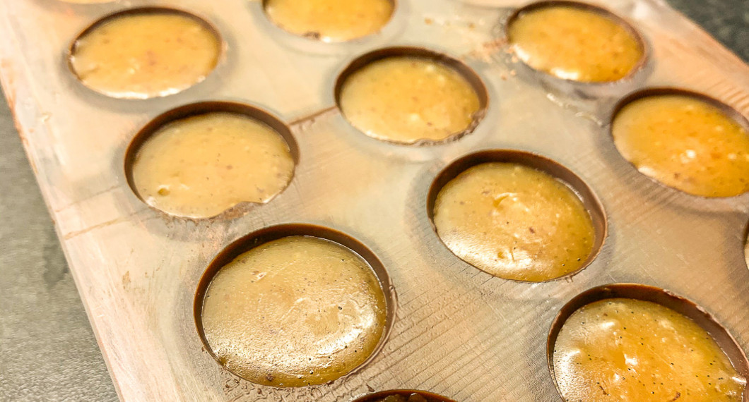 Smörkolan spritsas i pralinfacken som tidigare gjutits med choklad