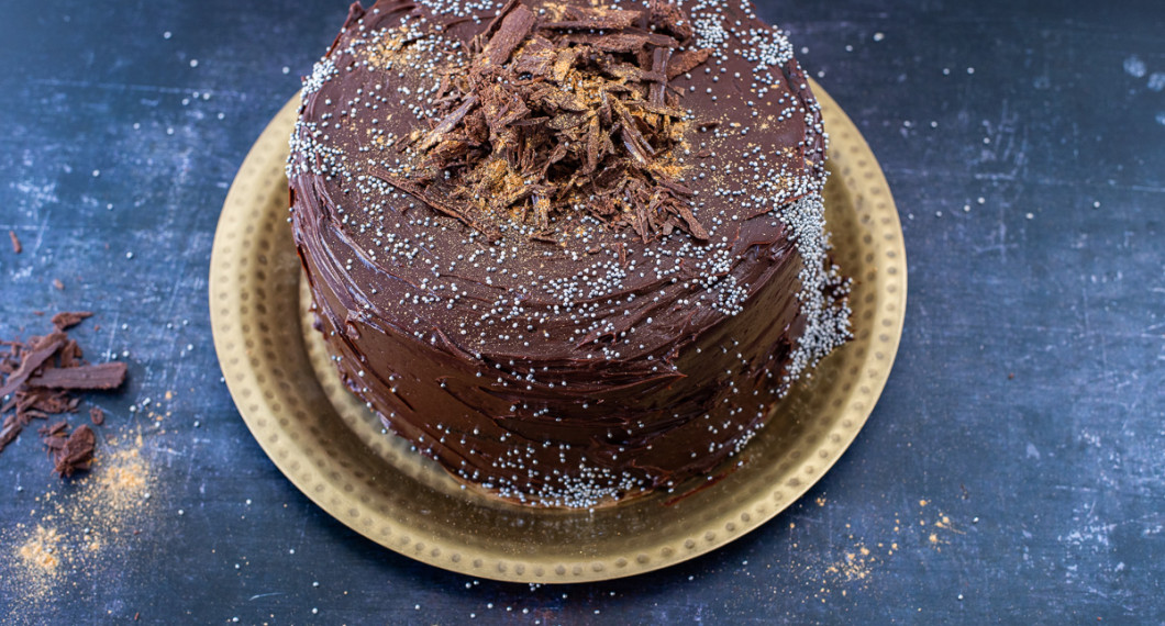 Den färdiga tårtan till servering garnerad med en hög strimlad choklad, strössel av silverkulor och guldpulver. 