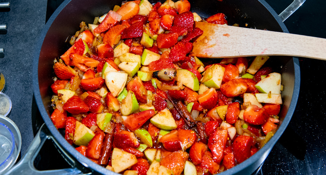 Jordgubbar, äpple, chili med flera ingredienser kokas i panna till chutney