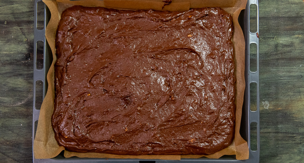 Häll smeten i en långpanna med bakplåtspapper i botten. Sprid ut smeten i ett jämnt lager med en slickepott. 