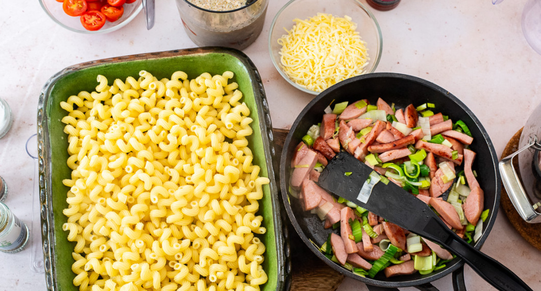 Lägg kokt pasta i en ugnsform med höga kanter. Skölj och dela cocktailtomater. 