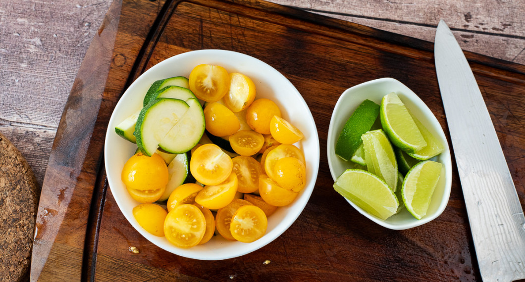 Skölj och skär zucchini i bitar samt cocktailtomater i halvor. 