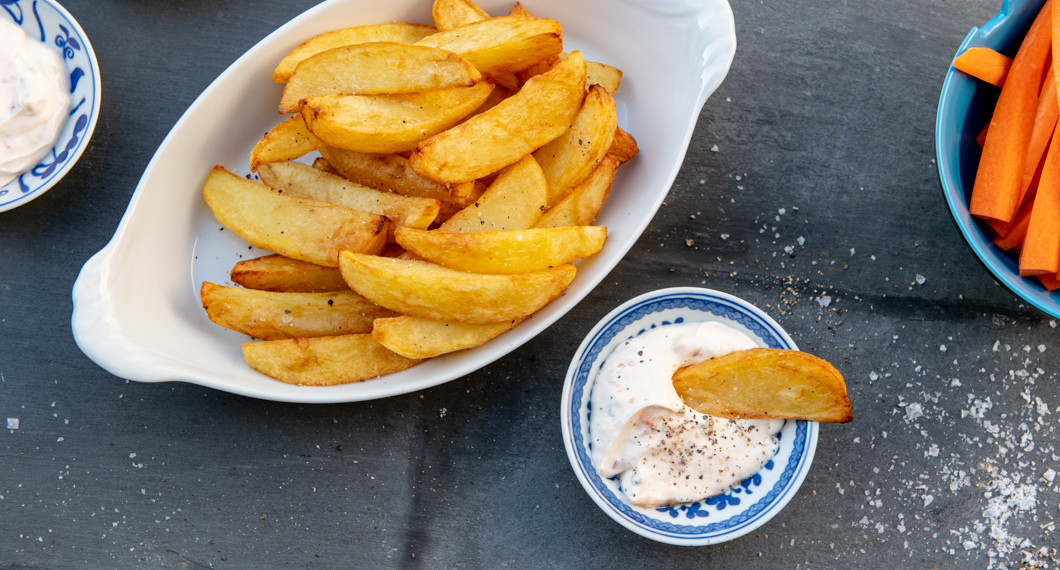 Friterad klyftpotatis på fat med dippsås och morotsstavar