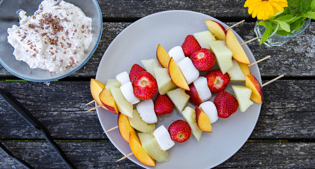 Fruktspetten innan grillning på tallrik med Daimgrädden vid sidan. 