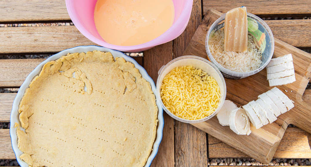 Ingredienser till Quiche Lorraine - äggstanning, förgräddat pajskal, getost i rulle, riven chevrette och lagrad ost. 