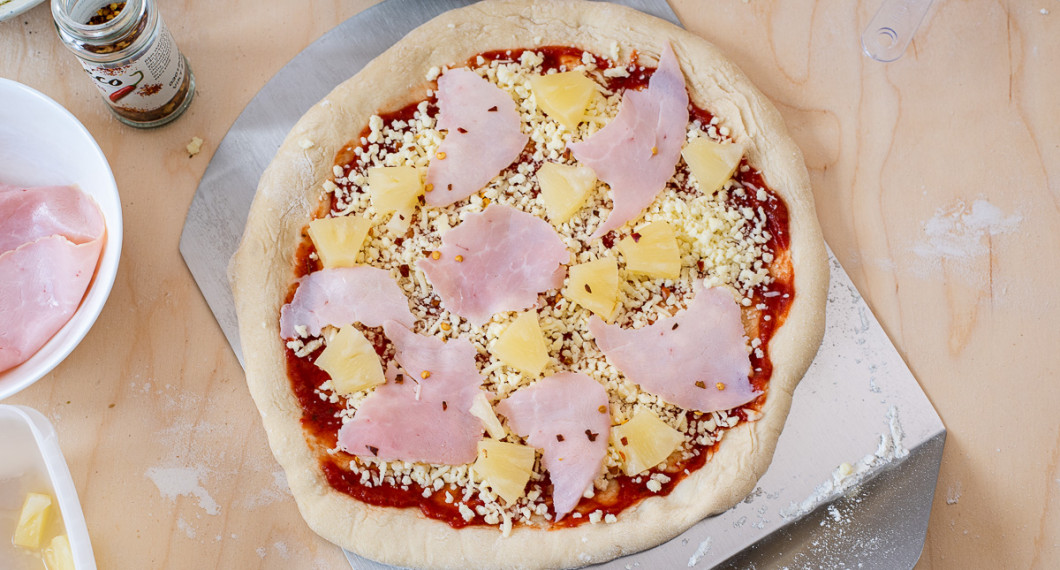 Bred ut pizzasås, ost, skinka och bitar av ananas. Strö vidare över lite chiliflakes om du önskar det. 