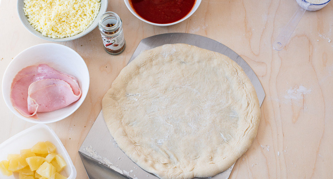 För över pizzabottnen till en mjölad pizzaspade. 