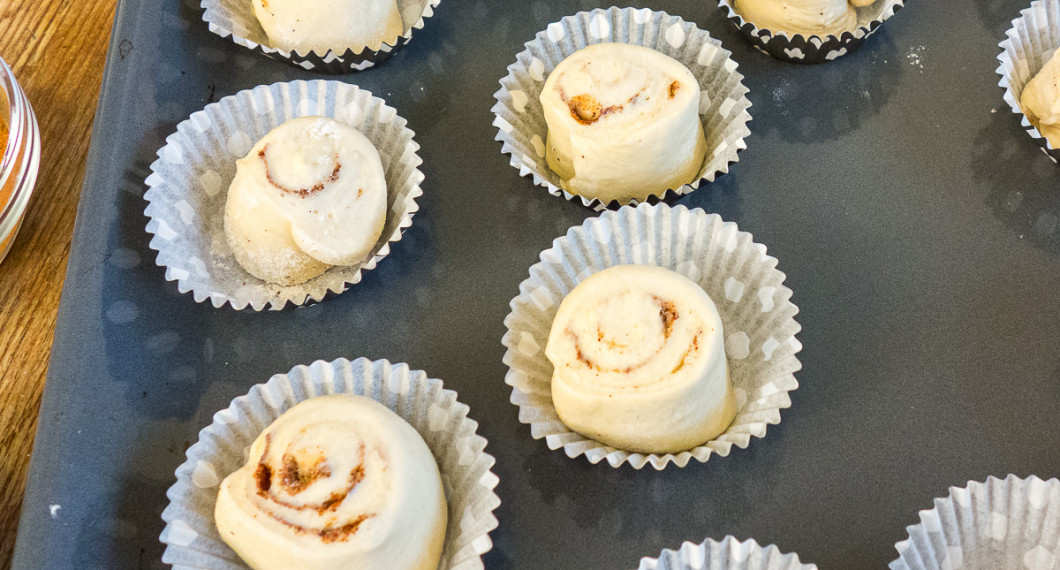 Kanelbullarna får jäsa i bakformar för att sedan penslas med uppvispat ägg samt beströs med pärlsocker. 