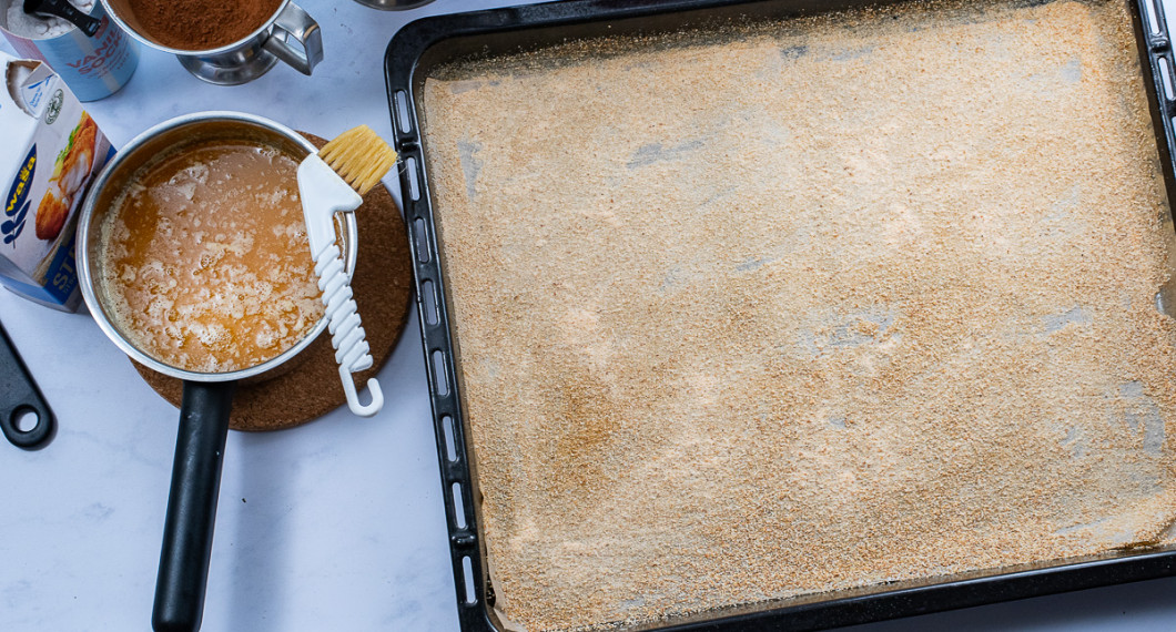 Smält smöret samt låt svalna något. Smörj en långpanna med bakplåtspapper i botten med lite av det smälta smöret och bröa med ströbröd. 