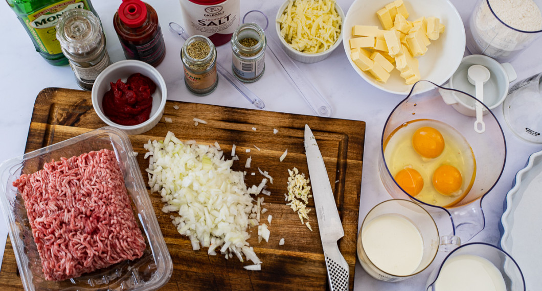 Ingredienser till köttfärspajen: köttfärs, olivolja, svartpeppar, tomatpure, sambal oelek, gul lök, vitlök, oregano, rosmarin, salt, riven ost, smör, ägg, grädde, mjölk och vetemjöl. 