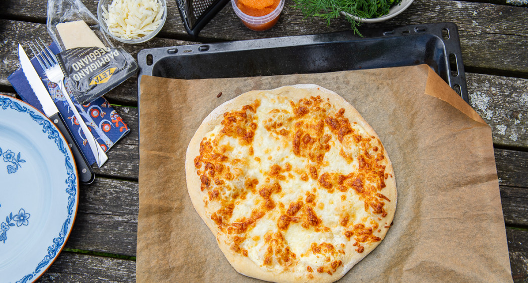 Grunden till pizzan är bakt och redo att toppas med löjrom, riven parmesan, pecorino, dill och grönkål. 