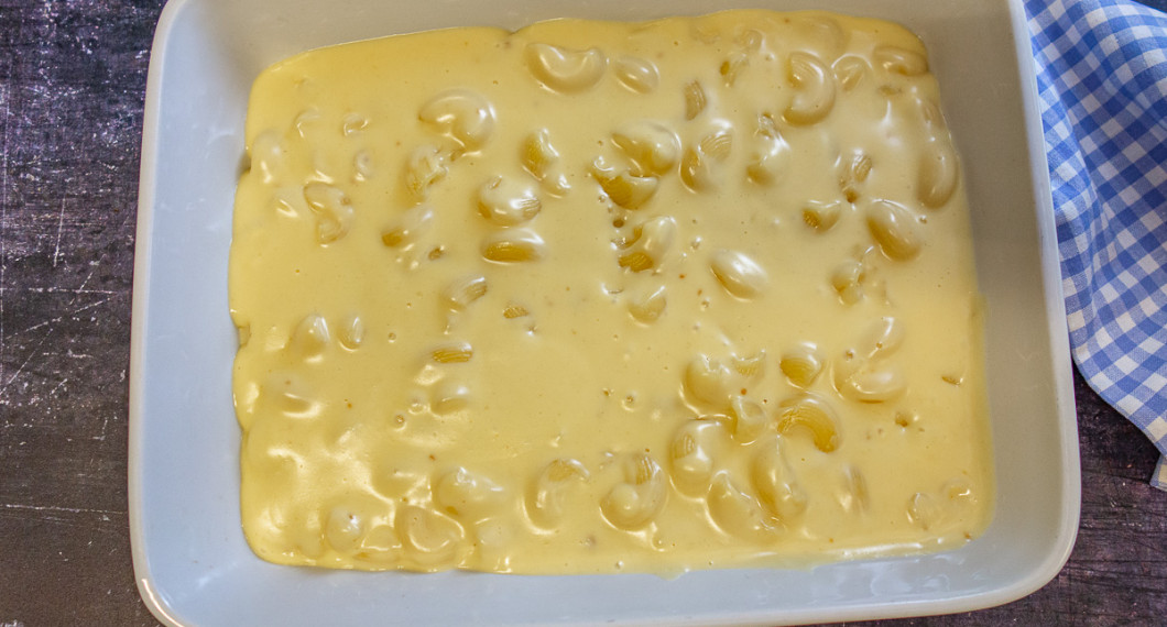 Makaronerna blandas med sås och ost samt breds ut i en ugnsfast form. 