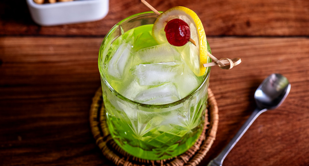 Drinken får en festliga färger med grön melonlikör, rött körsbär och gul citron. 