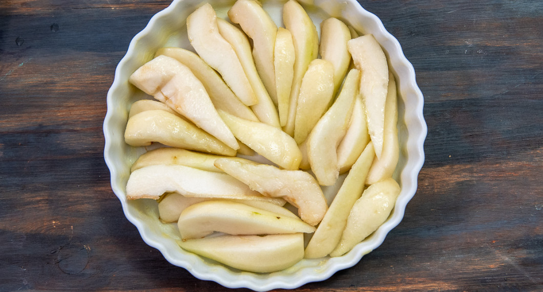 Skala, kärna ur och skär päron i bitar. Lägg i en pajform smord med smör. 