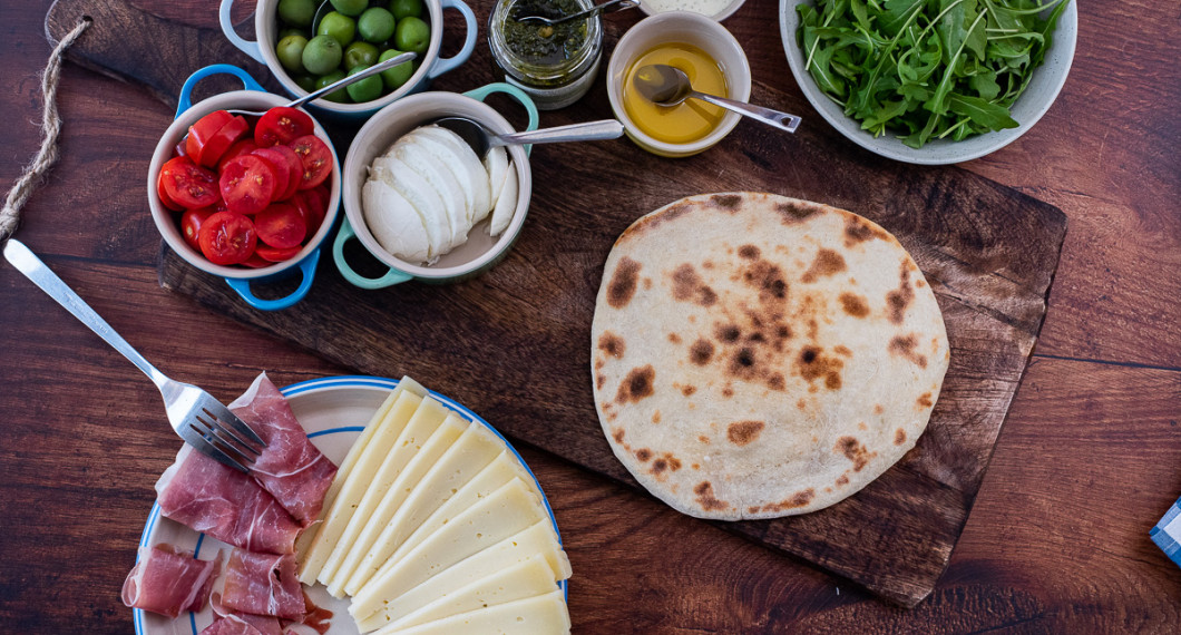 Piadina med prosciutto, pecorino, tomat, mozzarella, oliver, pesto, olivolja, balsamico, basilikakräm och ruccola. 