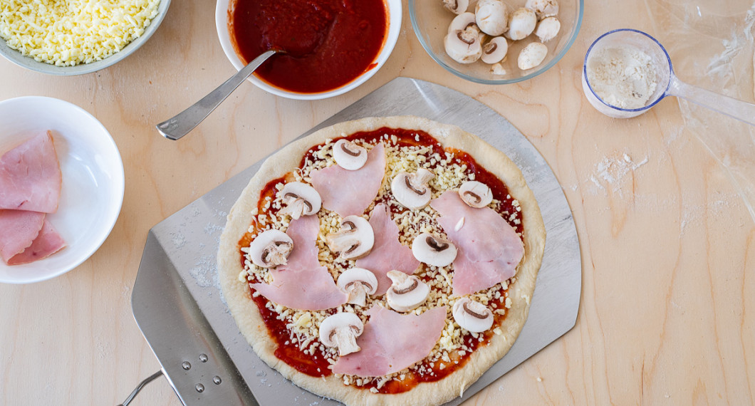 Bred ut pizzasås, ost, skinka och skivade champinjoner. 