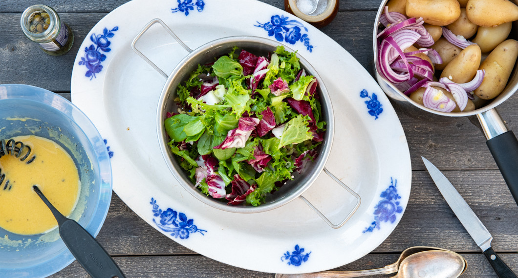 Salladsdressing, grönsallad samt kokt potatis med skivad rödlök. 