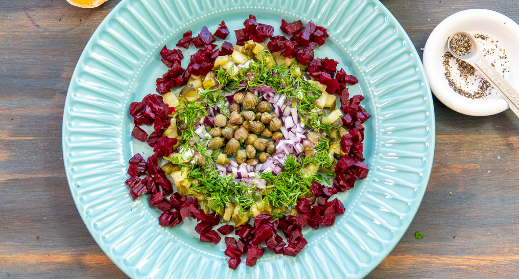 Lägg en ring rödbetor samt lägg hackad dill på ansjovisen. 