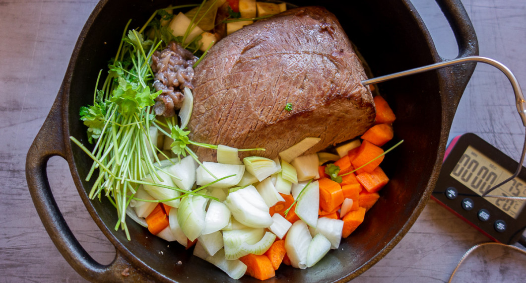 Steken bryns och läggs med grönsaker runt i grytan samt en stektermometer i mitten av köttet. 