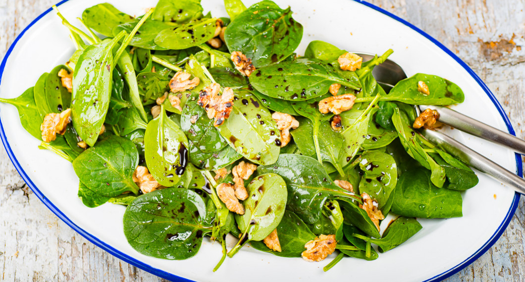 Spenatsallad med rostade valnötter och balsamvinäger på fat till laxen. 