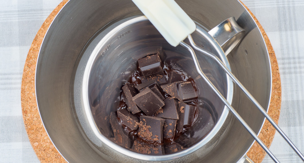 Choklad i bitar i bunke med vattenbad reda att tempereras. 