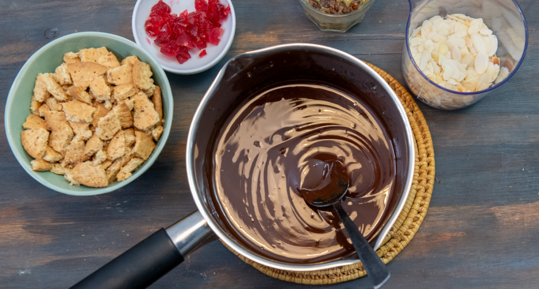 Smält chokladen och förbered krossade kex, hackade cocktailbär, russin och mandelspån. 