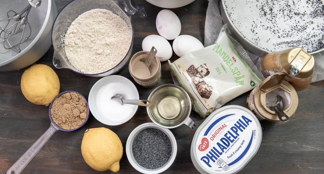 Till kakan behöver du citron, muscovadosocker, mandelmjöl, salt, vallmofrön, solrosolja, bakpulver och ägg. Till frostingen behöver du färskost, vaniljsocker, honung, mandelspån och florsocker (utanför bild). 