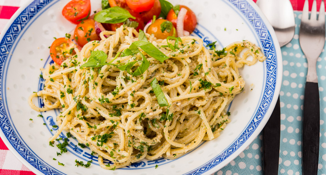 Solrospeston blandad med spagetti och serverad på tallrik med tomatsallad. 