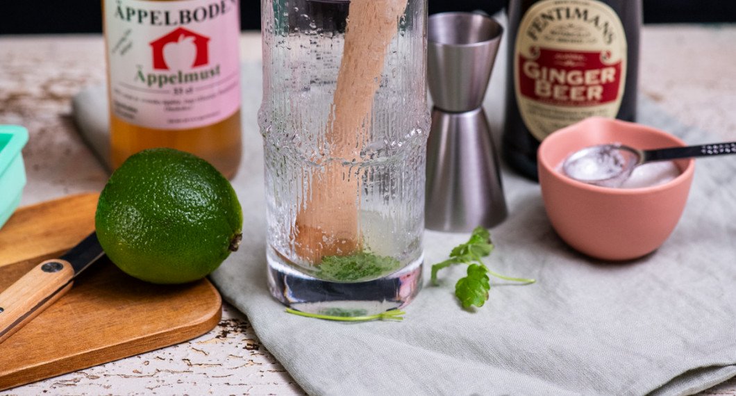 Muddla eller krossa myntablad med socker i botten på glaset. Tillsätt sedan lime, is, äppelmust och Ginger beer. 
