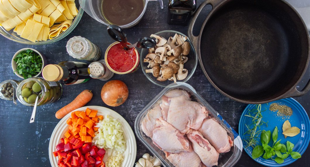 Ingredienser till cacciatore kycklinggryta: lagerblad, färsk basilika, rosmarin, timjan, oregano, kycklingdelar, hackad vitlök, lök, paprika och morot; skalade tomater på burk; kastanjechampinjoner, kycklingbuljong, vitt vin, olivolja samt italienska gröna oliver, kapris, persilja och pappardelle pasta till servering. 