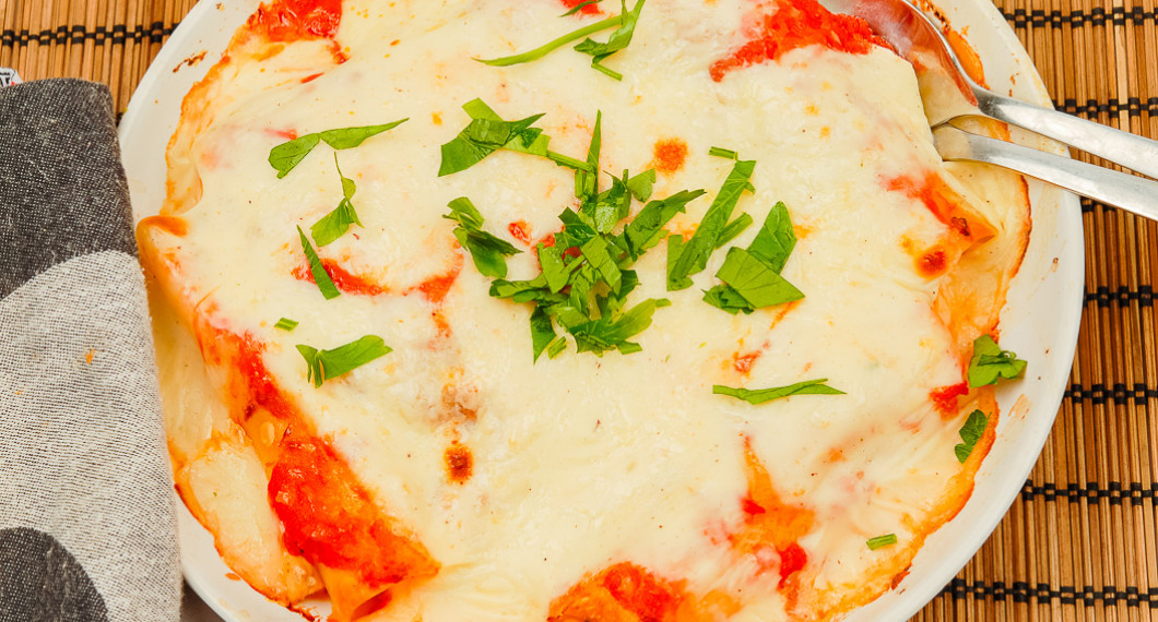 En ugnsform med cannellonis toppad med hackad persilja