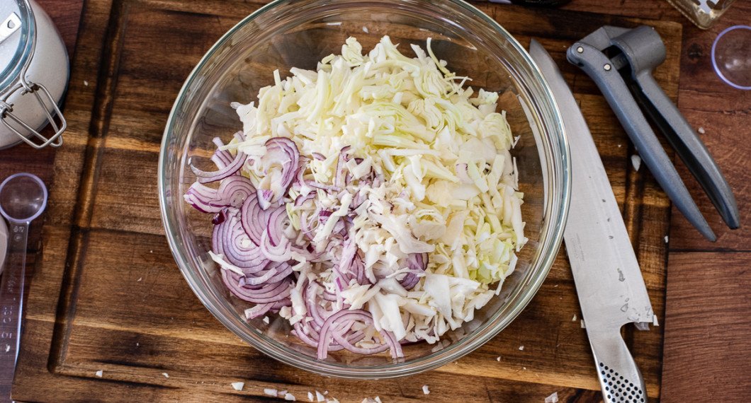 Strimla vitkål och rödlök samt lägg med salt, vinäger och socker i en bunke. 