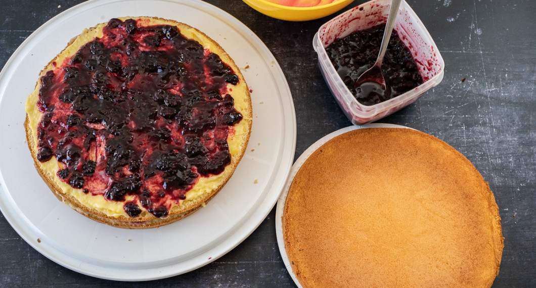Vaniljkräm och sylt bres på andra tårtbottnen. 