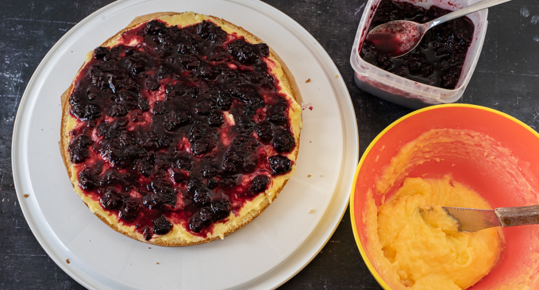 Vaniljkräm och sylt bres på första tårtbottnen. 