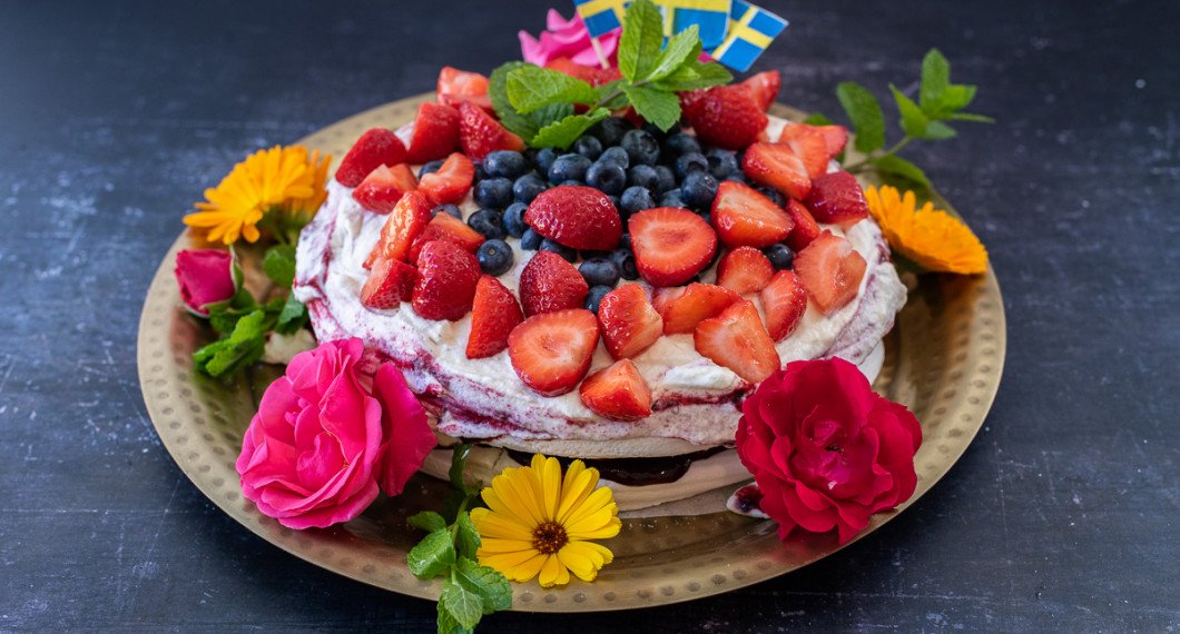 Jag garnerade marängtårtan med blåbär i mitten, jordgubbar runt samt flaggor, gröna blad av citronmeliss och blommor - ringblommor och rosor runt på fatet. 