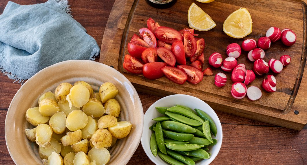 Kokt färskpotatis, salladsärtor, tomatklyftor, skivade rädisor, citron och olivolja till salladen. 