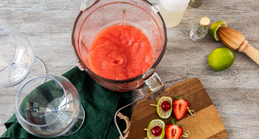 Is, lime, romessens, sockerlag och jordgubbar mixas till en slushig isröra. 