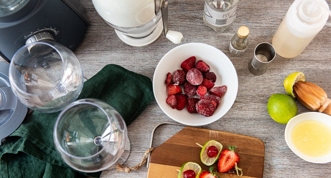 Ingredienser till den alkoholfria jordgubbsdaiquirin: krossad is, vichyvatten, sockerlag, ljus romessens, frysta jordgubbar, färskpressad lime och garnering med lime, cocktailbär och jordgubbe på bampuspett.  