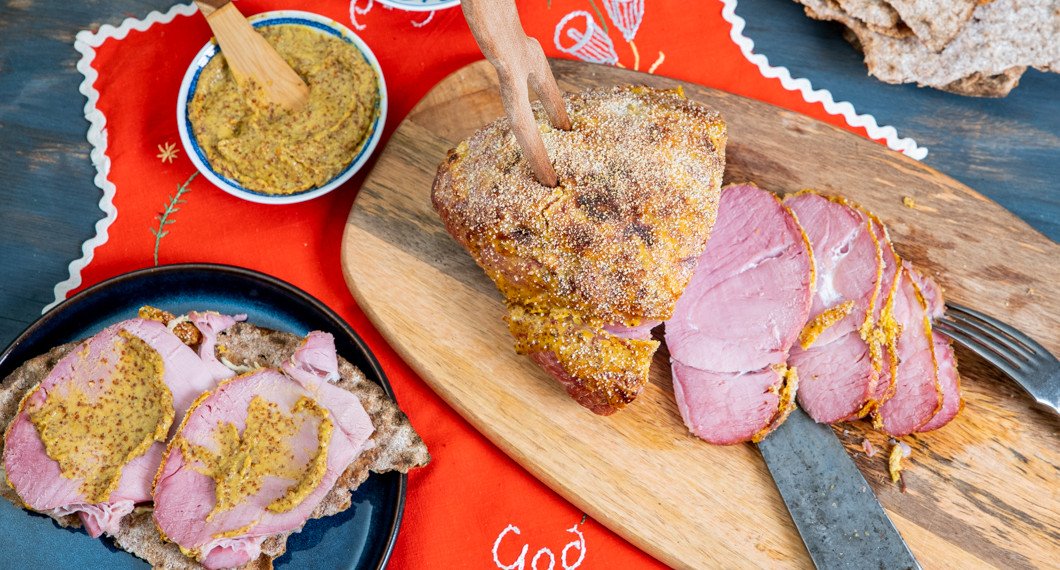 Julskinkan serverad på skärbräda med senap, smör och knäckebröd