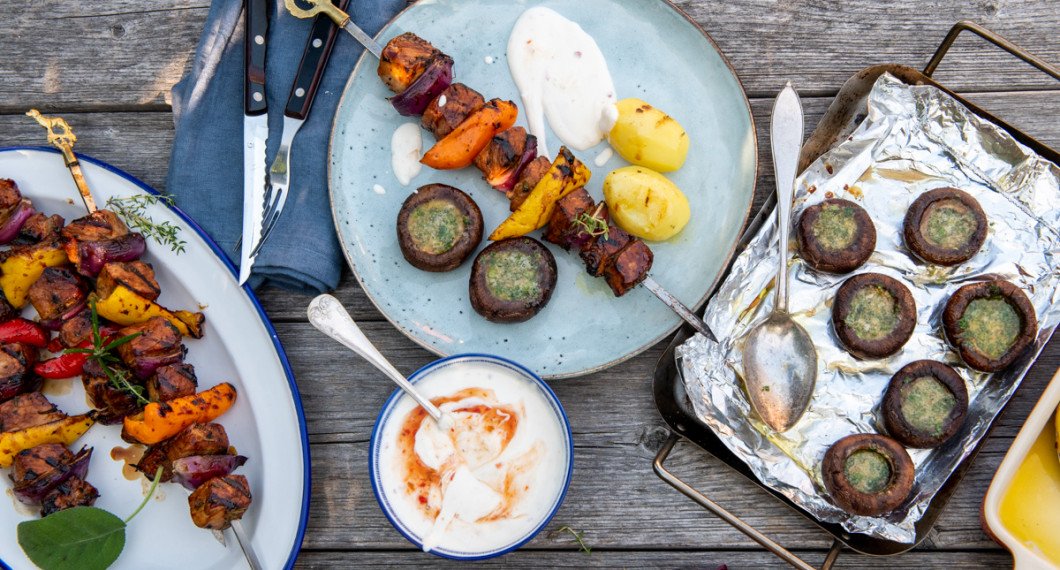 Grillad fast skalad potatis serverad till spett med fläskytterfilé och grillade vitlöksfyllda champinjoner. 