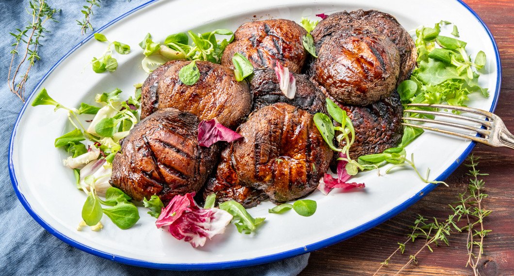 De grillade portabellosvamparna på fat med garnering av grön sallad och timjan